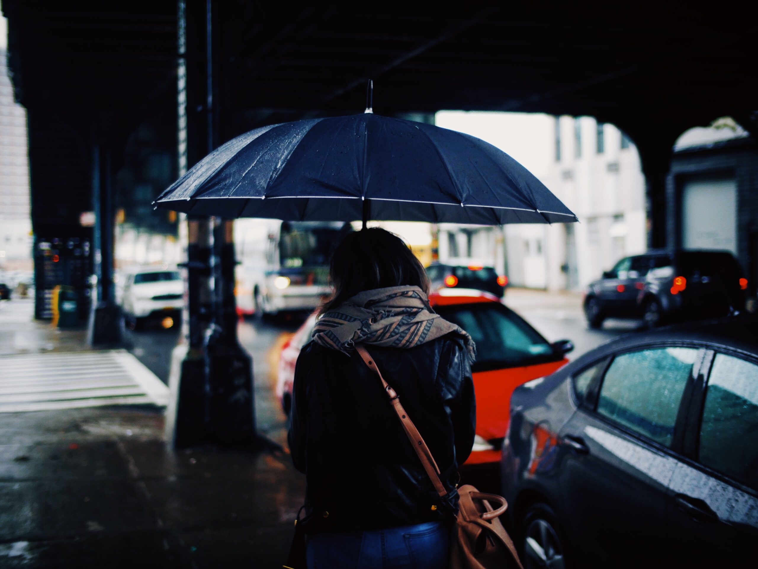 Pessoa caminhando na rua com guarda-chuva durante chuva